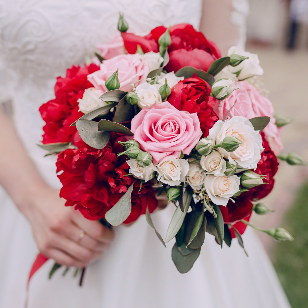 Bridal bouquet featuring red roses and white florals, symbolising love and elegance.